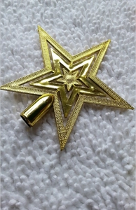 Close-up of golden glitter Christmas tree topper with hollow pentagram and metal finish