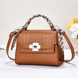 Détail du sac à main marron à motif crocodile avec fermoir argenté et foulard en soie