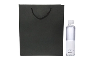 Matte black paper gift bag with rope handles shown next to a water bottle for size scale