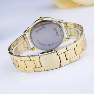 Detail view of the gold-tone metal watch band and stainless steel back case engraving