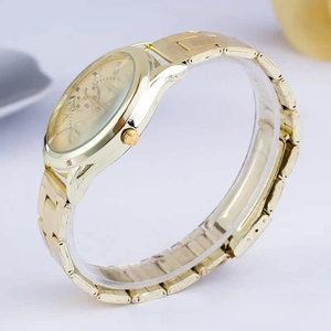 Detail view of a gold Geneva quartz watch with Roman scale and polished metal link bracelet