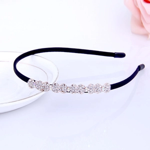 Detailed close-up of a black rhinestone headband with floral decor on a ceramic plate
