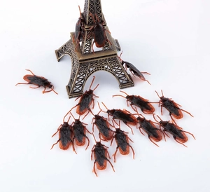 Detailed macro view of realistic prank cockroaches crawling on a small Eiffel Tower model