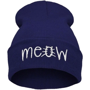 Close-up detail of white meow embroidery with cat ears on deep blue knitted beanie cap