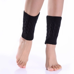 Close-up of black cable knit leg warmers showing the thick texture and elastic ribbed cuffs