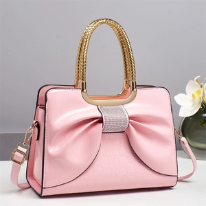 Pink faux croc leather handbag with large rhinestone bow and woven gold handle