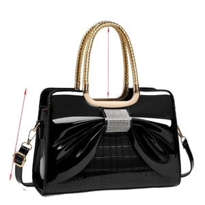 Elegant black patent leather handbag with bow detail and gold circular woven handles