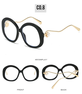Detail view of oval black sunglasses with gold wavy temples and pearl accents on the side