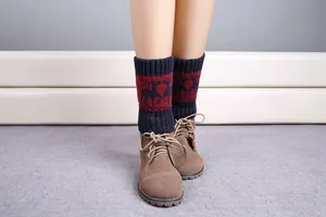 Detail of knitted leg warmers with reindeer pattern and wine red ribbed trim on boots