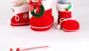 Detail of red Christmas boots gift bag with white fur trim and decorative snowflake patterns