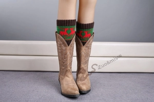 Close-up of knit Christmas leg warmers with red reindeer pattern worn with tan boots
