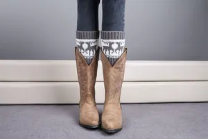 Close-up of knit leg warmers with reindeer patterns and vintage brown leather boots