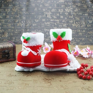 Detail of red flocked Christmas boot gift bags with white fur trim and holly decorations