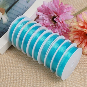 Detailed stack of ten light blue elastic crystal beading threads on plastic spools