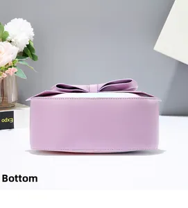 Detailed bottom view of purple leather crossbody bag featuring a large decorative bow