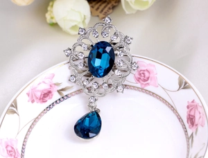 Detail of a vintage brooch with dark blue stones and crystals on a floral plate