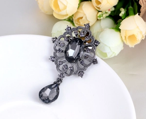 Detailed view of a vintage gunmetal brooch with sparkling rhinestones on a white plate