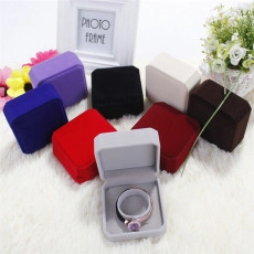 Flat lay of velvet jewelry boxes in multiple colors on a soft white plush rug background