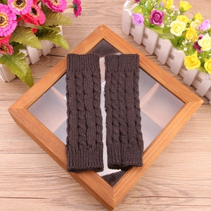 Winter cable knit fingerless gloves in dark brown displayed on a wooden tray