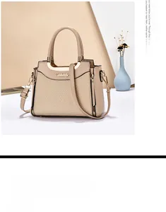 Detail of beige tote bag featuring lychee texture leather and gold metal hardware logo
