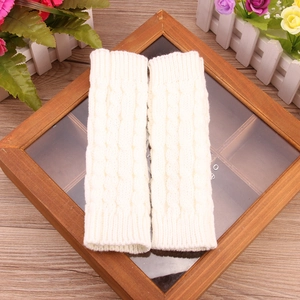 Detail of white cable knit arm warmers with thick textured weave and ribbed cuffs
