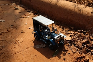 Détail d'une voiture miniature vintage en métal bleu avec finitions industrielles rouillées