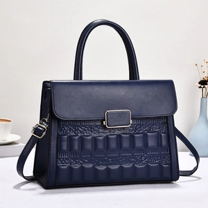 Macro view of navy blue leather handbag featuring square embossed patterns and gold buckle