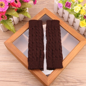 Detail shot of dark brown cable-knit fingerless gloves showing thick texture and pattern