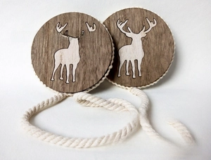 Close-up of wooden magnetic curtain tie-backs with white deer silhouette and cotton rope
