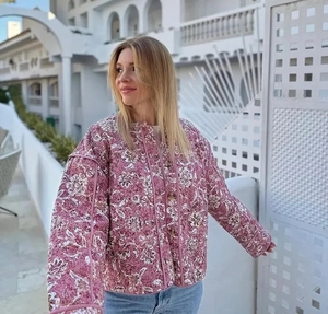 Détail de la veste matelassée fleurie avec col rond et boutons foncés sur tissu rose