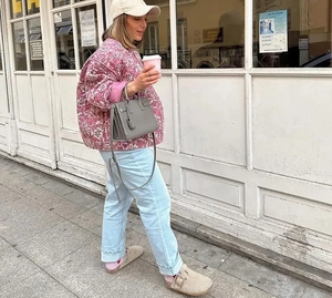 Détail de la veste matelassée fleurie rose portée avec un jean bleu et des mules