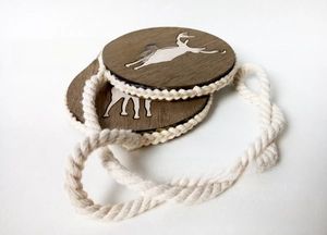 Detail of wooden curtain tieback with reindeer laser-cut design and braided rope