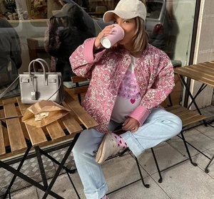 Détail d'une veste matelassée en coton rose à fleurs avec un jean et une casquette