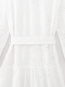 Detailed close-up of white broderie anglaise embroidery dress with matching waist belt