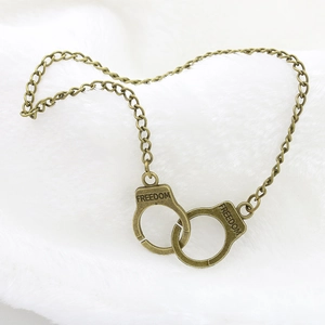 Macro detail of vintage bronze handcuff pendant with Freedom engraving on plush background