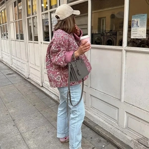 Veste matelassée rose à fleurs avec col rond présentée dans un style urbain décontracté