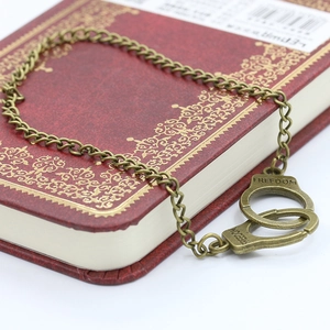 Close-up of vintage bronze handcuff pendant with FREEDOM engraving on a red book