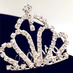 Detailed view of a silver crown hairpiece with rhinestones on black velvet