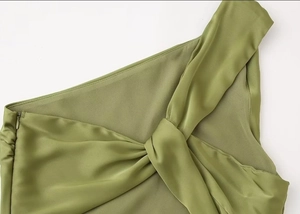 Detail of green satin dress featuring elegant twist design and hidden side zipper