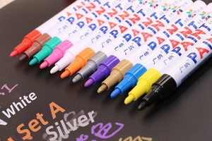 Detailed close-up showing vibrant multi-color oil-based paint markers on black surface