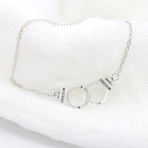 Detailed view of silver handcuff bracelet charm with FREEDOM engraving on soft fur