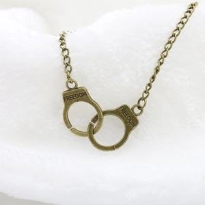 Macro view of vintage bronze handcuff pendant with FREEDOM engraving on white fur