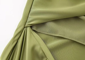 Close-up of olive green gradient satin dress with pleated twist texture and silky finish