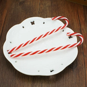 Close-up of red and white striped acrylic candy cane ornaments on a ceramic plate