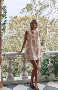 Détail d'une robe trapèze sans manches blanche avec fleurs rouges et motifs ondulés