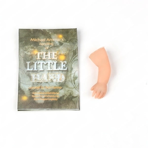 Close-up of magic trick set with a tiny plastic hand and The Little Hand instruction manual