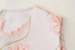 Détail du col rond et du bouton sur la robe en lin à imprimé floral rose