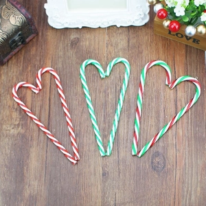 Detailed view of striped candy cane ornaments arranged in heart shapes on a wood surface