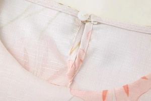 Détail d'une robe sans manches à imprimé floral rose avec texture lin et bouton au dos
