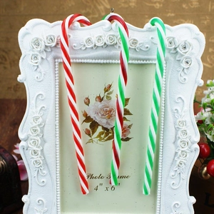 Christmas candy cane ornaments with red and white spiral stripes hanging on a white frame